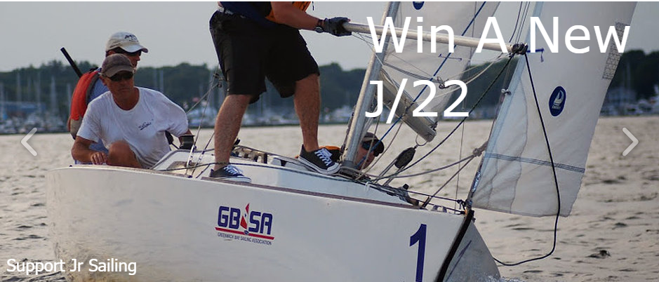 Three people sailing a white racing boat labeled “GBSA” and “1” on the water, with the text “Win A New J/22” overlaid. The shoreline and trees are visible in the background.