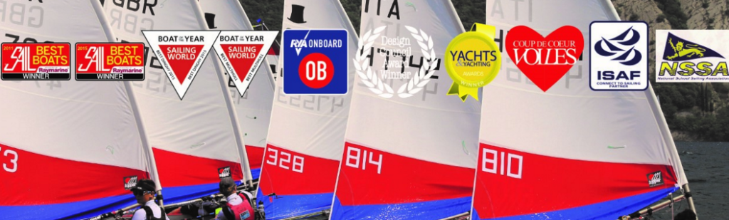 Four colorful sailboats with red, white, and blue sails race on the water; the sails display numbers and are aligned closely. Various award and recognition logos are overlaid across the top of the image.