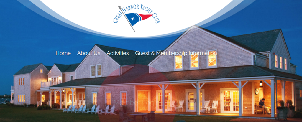 Large gray shingle-style building with white trim and a covered porch, set against a blue sky at sunset. Logo for Great Harbor Yacht Club is displayed above the navigation menu.