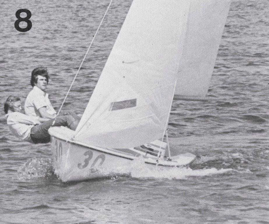 Two people sail a small dinghy with the number 30 on the hull, leaning out to balance the boat as it moves through the water. The image is in black and white, with the number 8 in the top left corner.