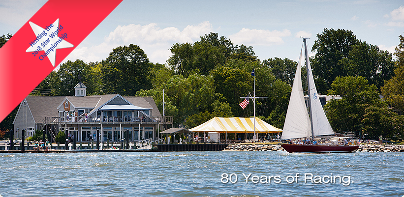 A sailboat glides on a lake near a waterfront building with a striped tent and trees. A red ribbon graphic with a blue star is on the left, and text at the bottom right reads: '80 Years of Racing.