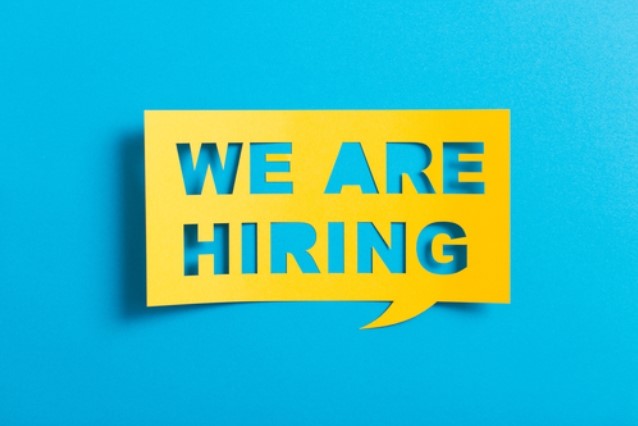 A yellow speech bubble with the words 'WE ARE HIRING' cut out, placed on a bright blue background.