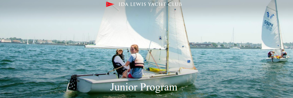 Two young sailors wearing life jackets navigate a small sailboat on a calm body of water, with another sailboat in the background. The text “IDA LEWIS YACHT CLUB” and “Junior Program” is overlaid on the image.