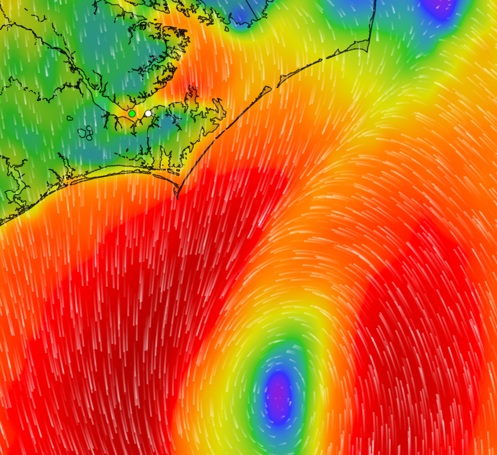 A colorful weather map shows wind patterns off the coast of North Carolina, with a distinct cyclone indicated by swirling lines and a blue center surrounded by red, orange, and yellow bands representing intensity.