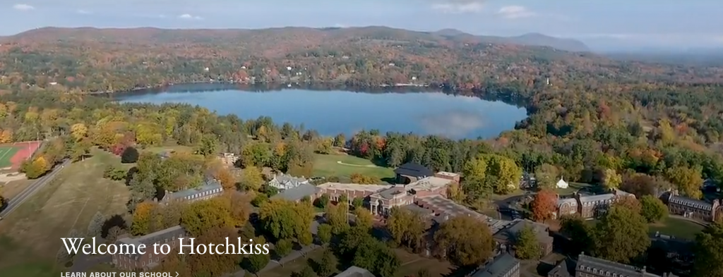 Aerial view of the Hotchkiss School campus surrounded by trees in autumn, with a large lake and mountains in the background. Text reads “Welcome to Hotchkiss.”.