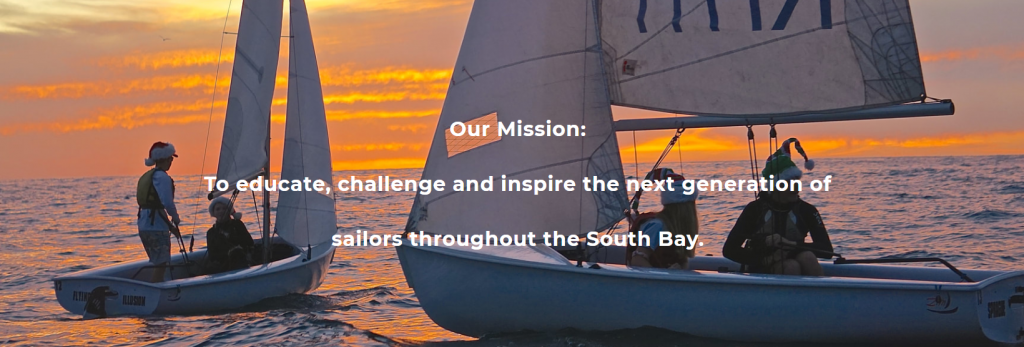 Four people sail two small boats on the ocean at sunset, with orange and purple sky in the background. Text over the image reads: 'Our Mission: To educate, challenge and inspire the next generation of sailors throughout the South Bay.