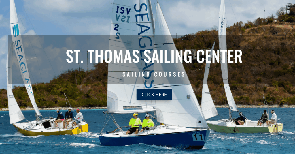 Four sailboats with people in bright clothing are sailing near a rocky, tree-covered coastline. Text over the image reads 'St. Thomas Sailing Center Sailing Courses,' with a button labeled 'Click Here.