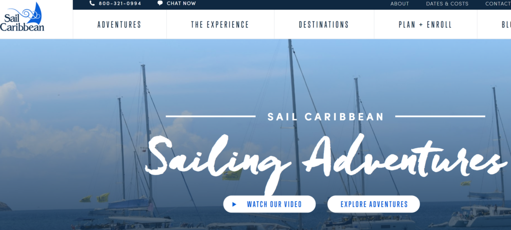 A website homepage for Sail Caribbean, featuring a blue header with navigation links and a background image of sailboats docked in the water under a clear sky. Buttons read 'Watch Our Video' and 'Explore Adventures.