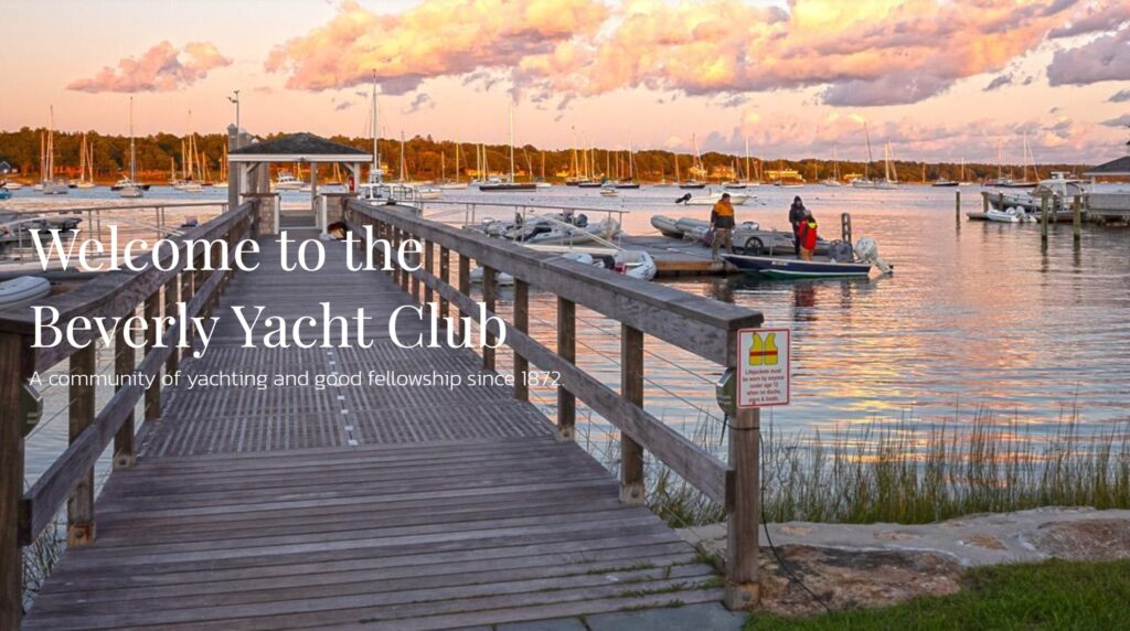 A wooden dock leads to a marina with several boats on calm water at sunset. Two people stand near the boats. Text reads 'Welcome to the Beverly Yacht Club, a community of yachting and good fellowship since 1872.